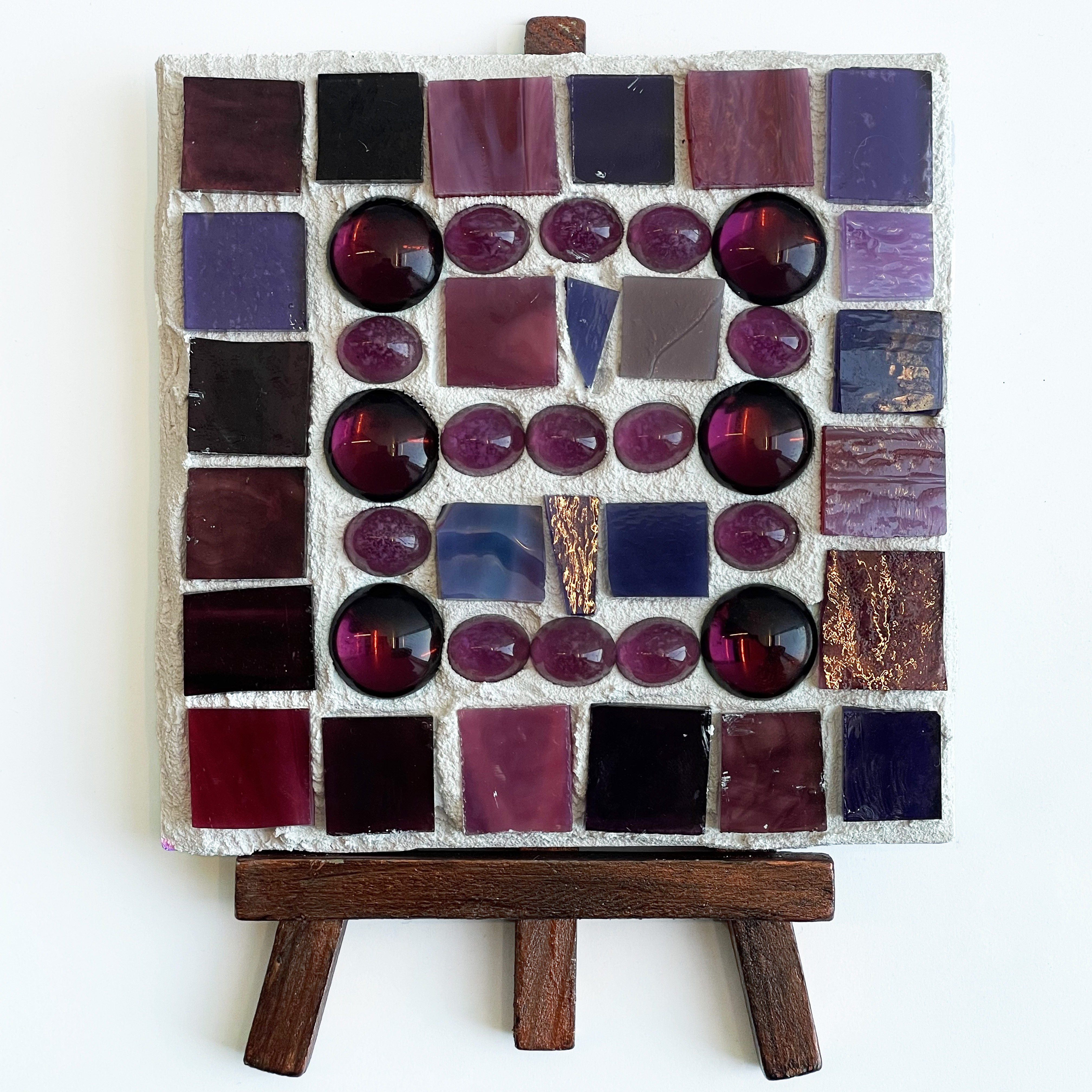 A square tile with colorful glass beads on it