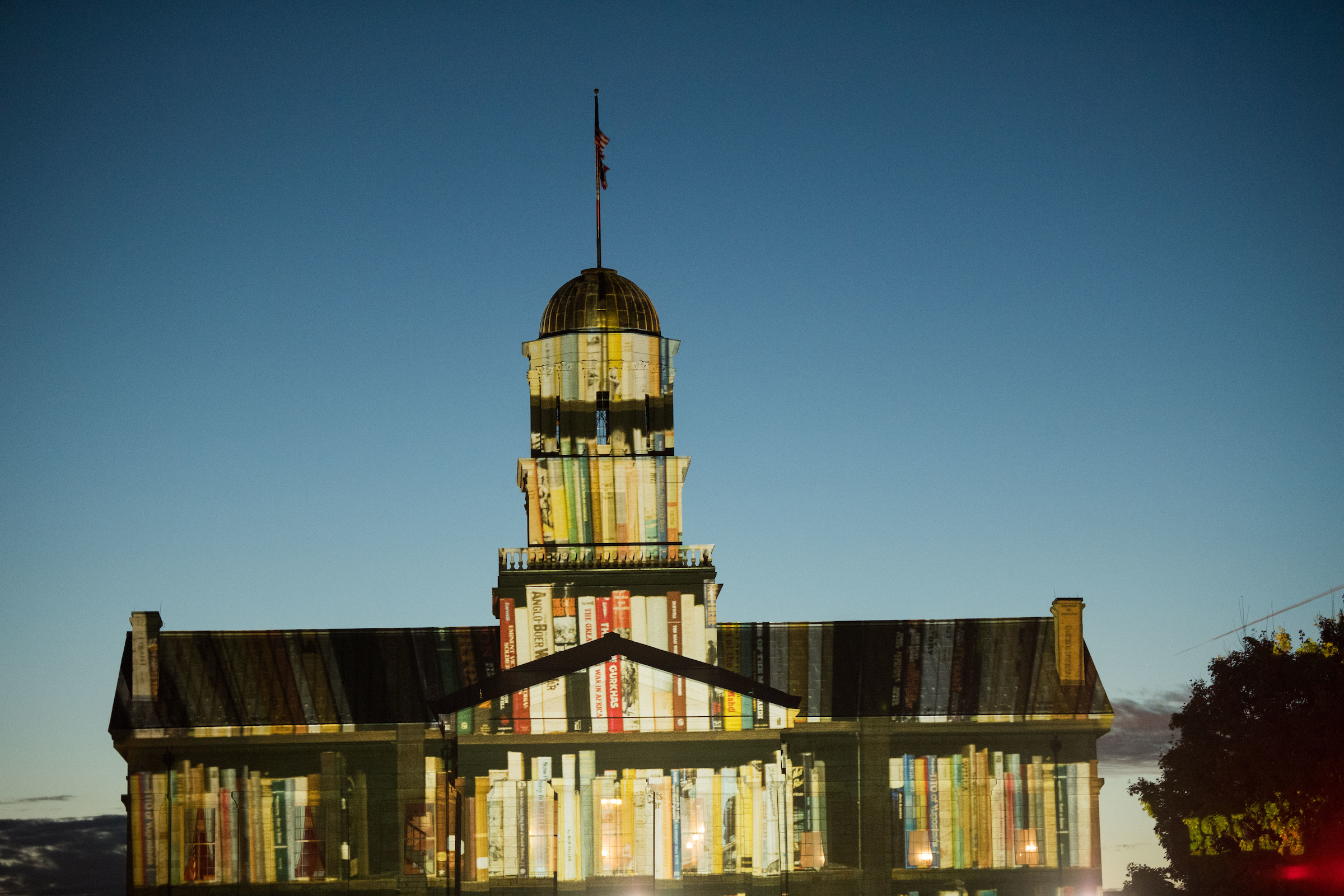 Image of Book spines projected onto the facade of the Old Capitol Building at dusk