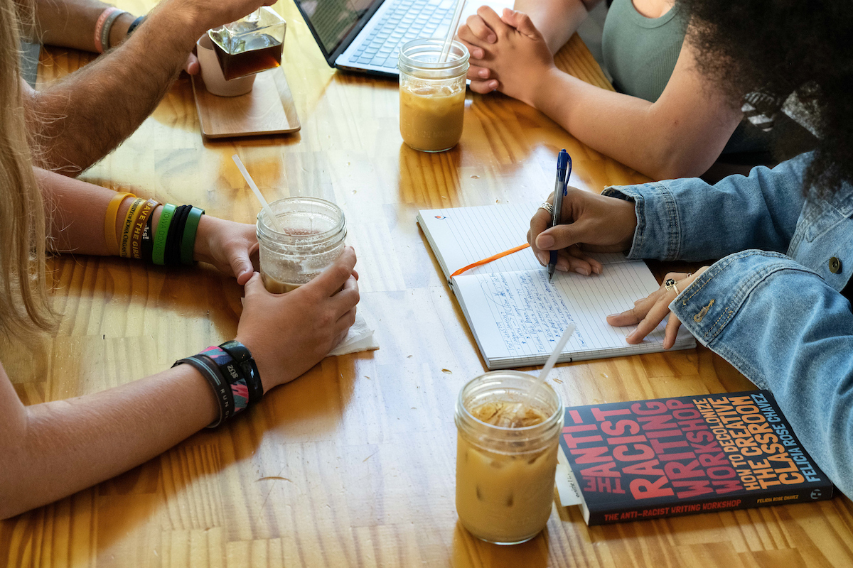 picture of students sitting at cafe table with mason jars of iced coffee on table