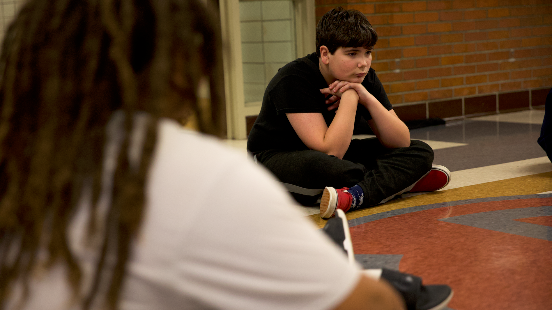 young boy sitting in school hallway