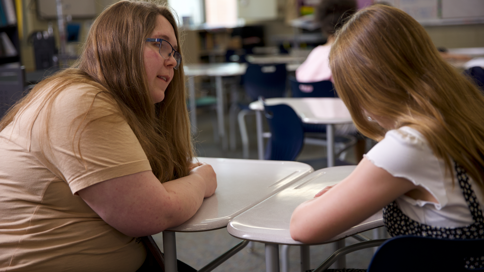 teacher and student talking at desk