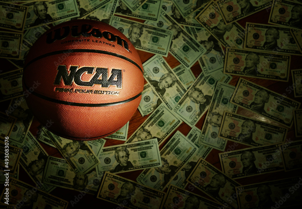 Basketball with NCAA logo, with $20 bills scattered on floor beneath it
