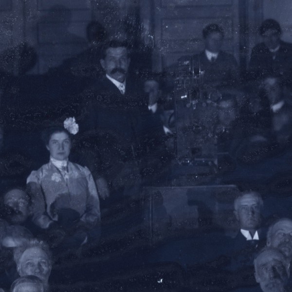 Brinton in a theater next to a movie projector surrounded by the audience.