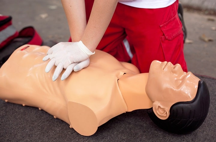 Someone doing chest compressions on a CPR dummy