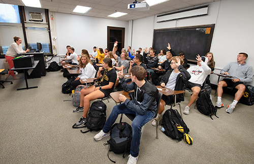 UI students participate in the first day of class by raising their hands during a discussion.