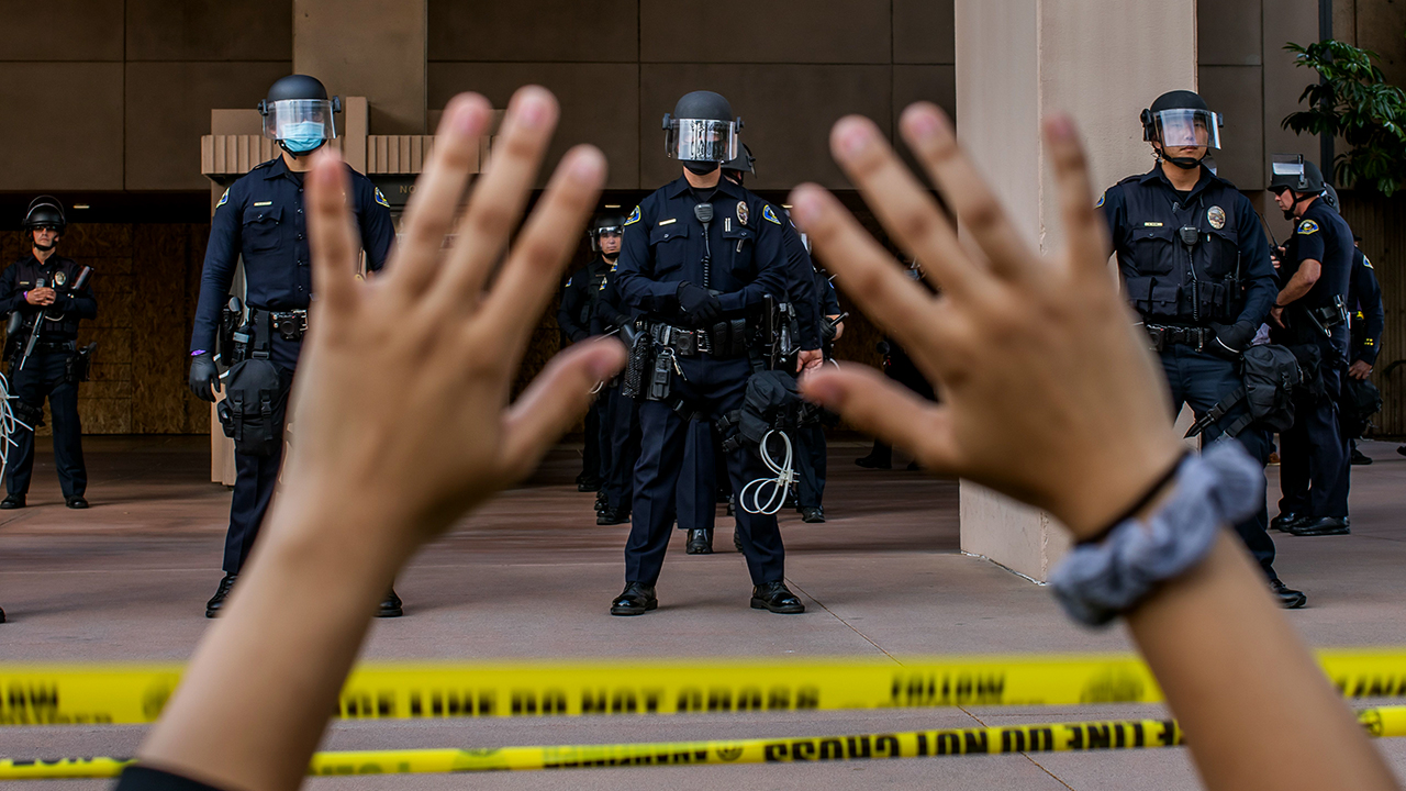 Police officers, hands up in foreground. Creator: APU GOMES | Credit: AFP via Getty Images