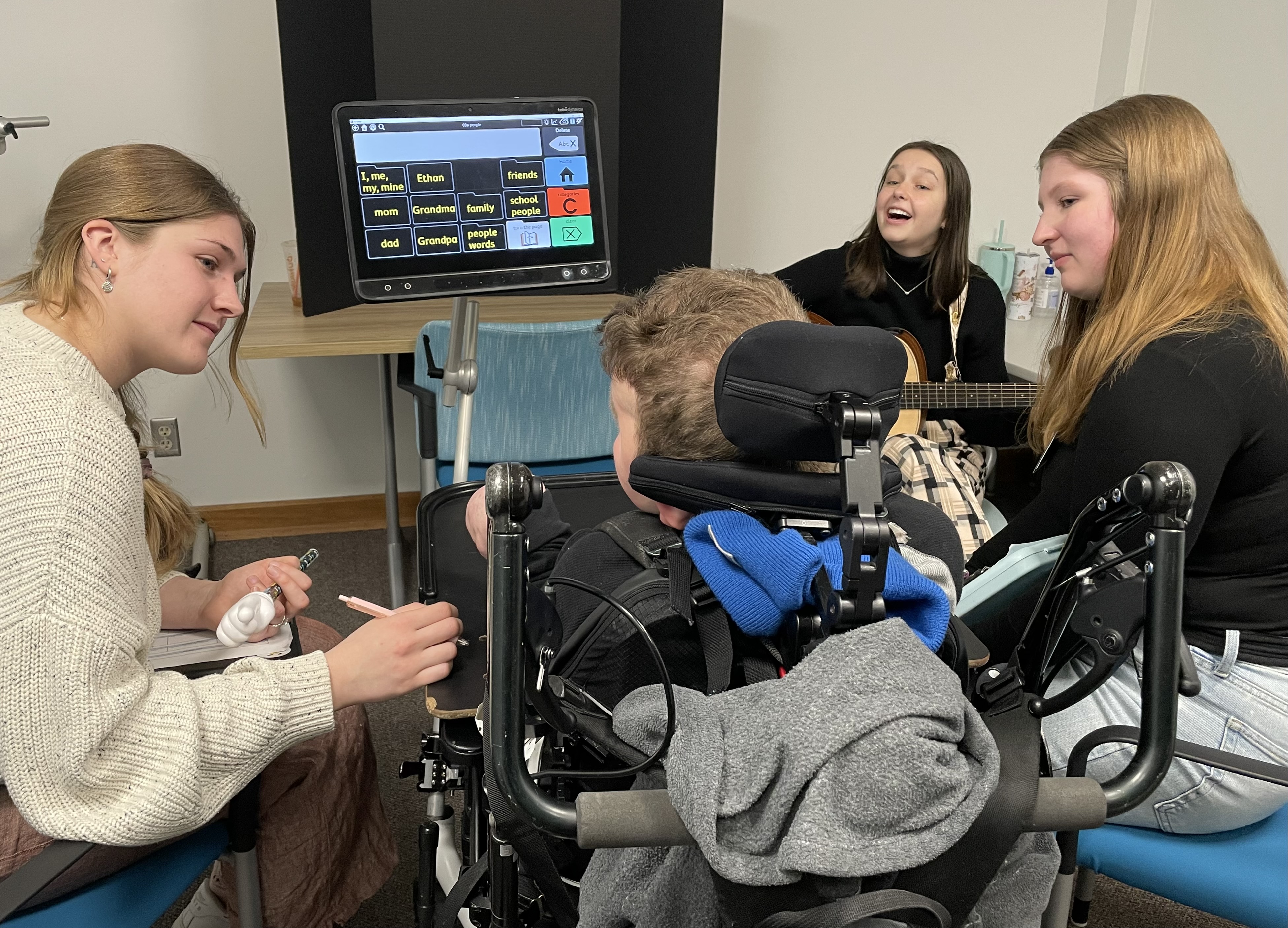 Music Therapy students providing therapy to a child using a motorized wheelchair