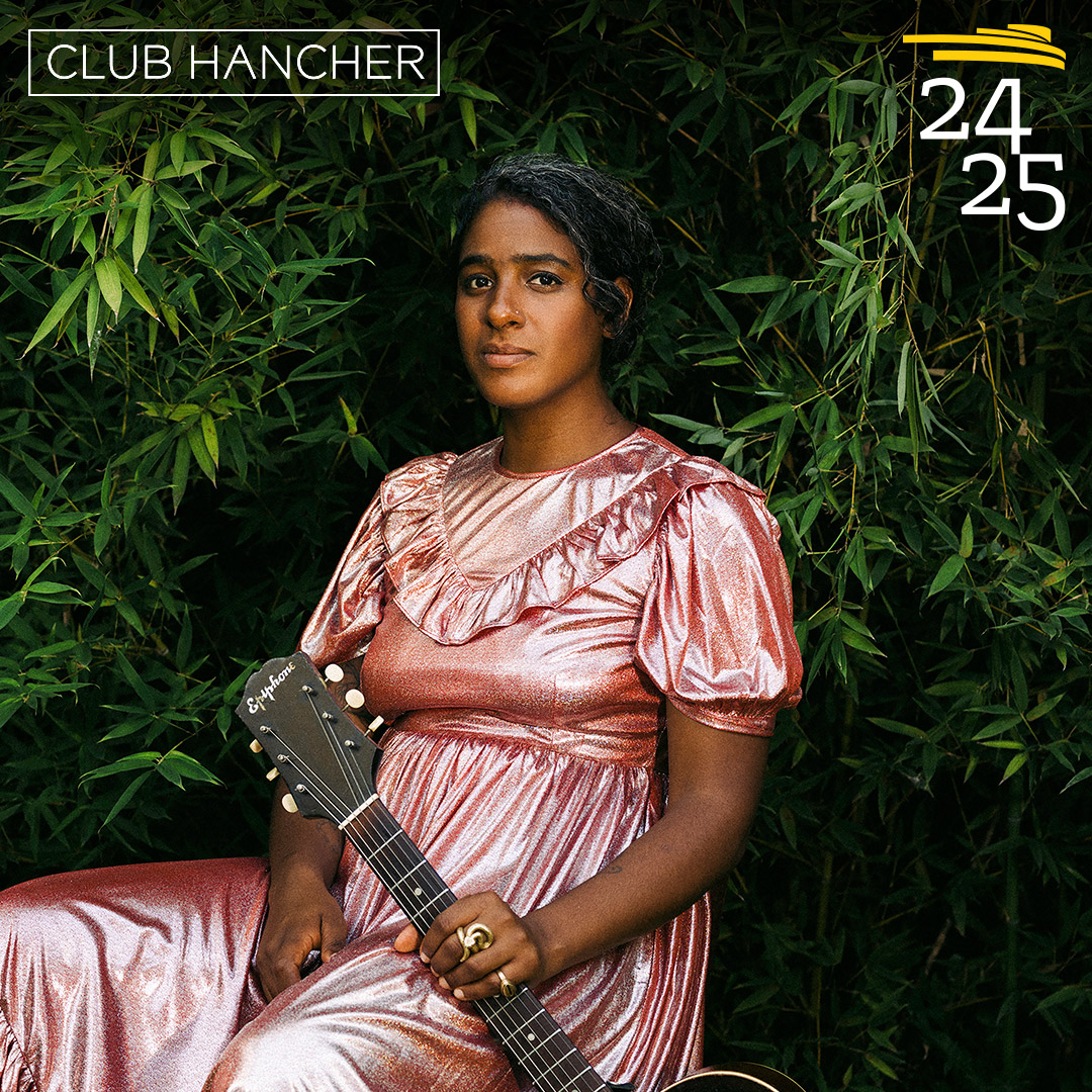 Leyla McCalla sitting in a pink dress against greenery holding her guitar to her left side. Club Hancher text treatment in upper left corner