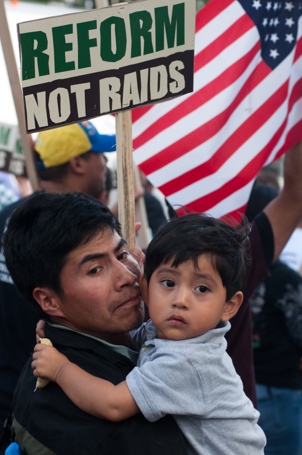 man holding child at an anti-ICE raid rally
