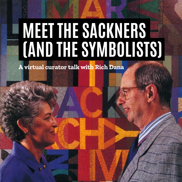 An joyful older white couple stand in profile and face one another. They are smiling and posing in front of a colorful piece of art that says "Sackner Archive."