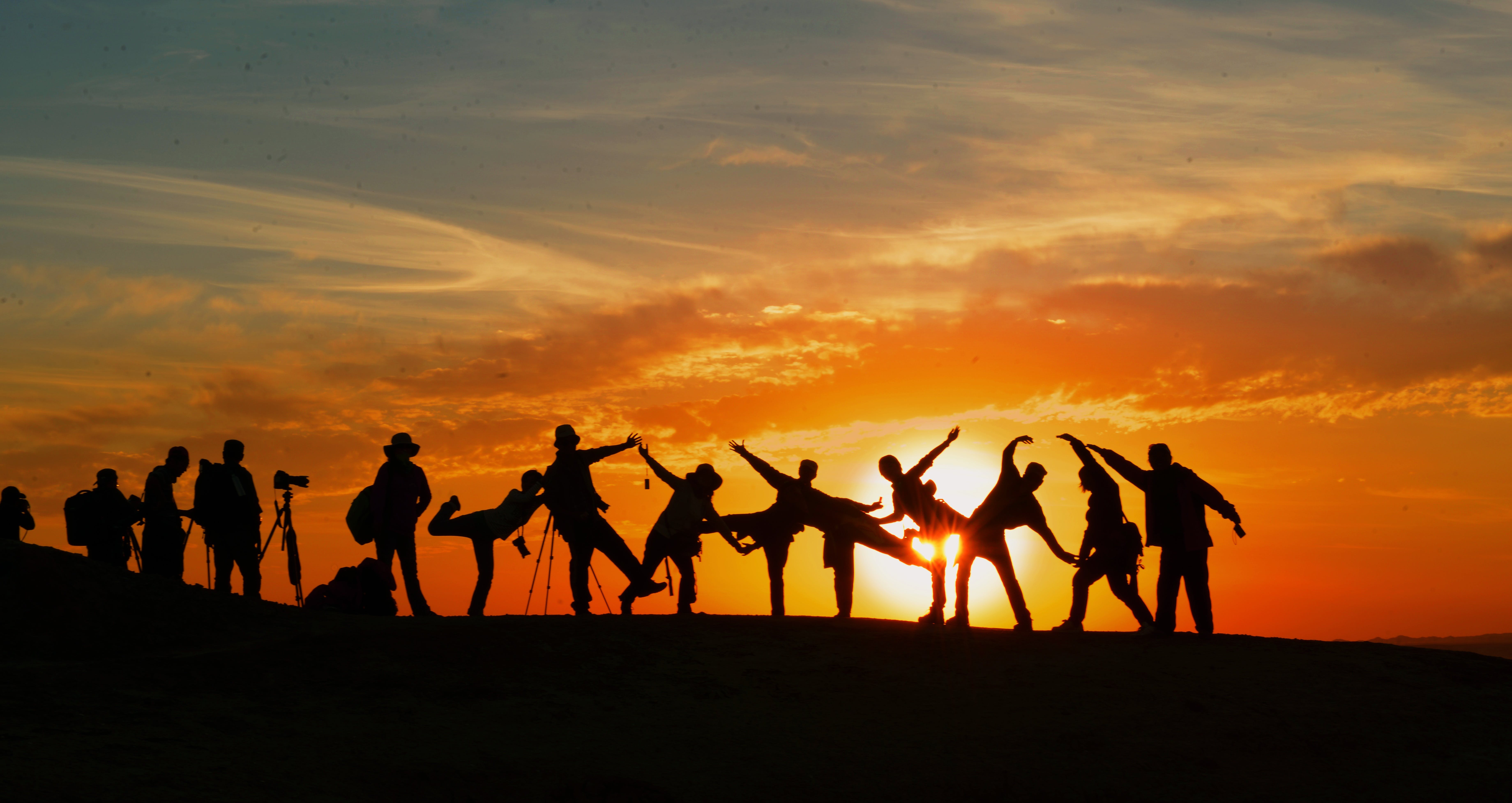 Silhouettes of people dancing, playing against the sunset