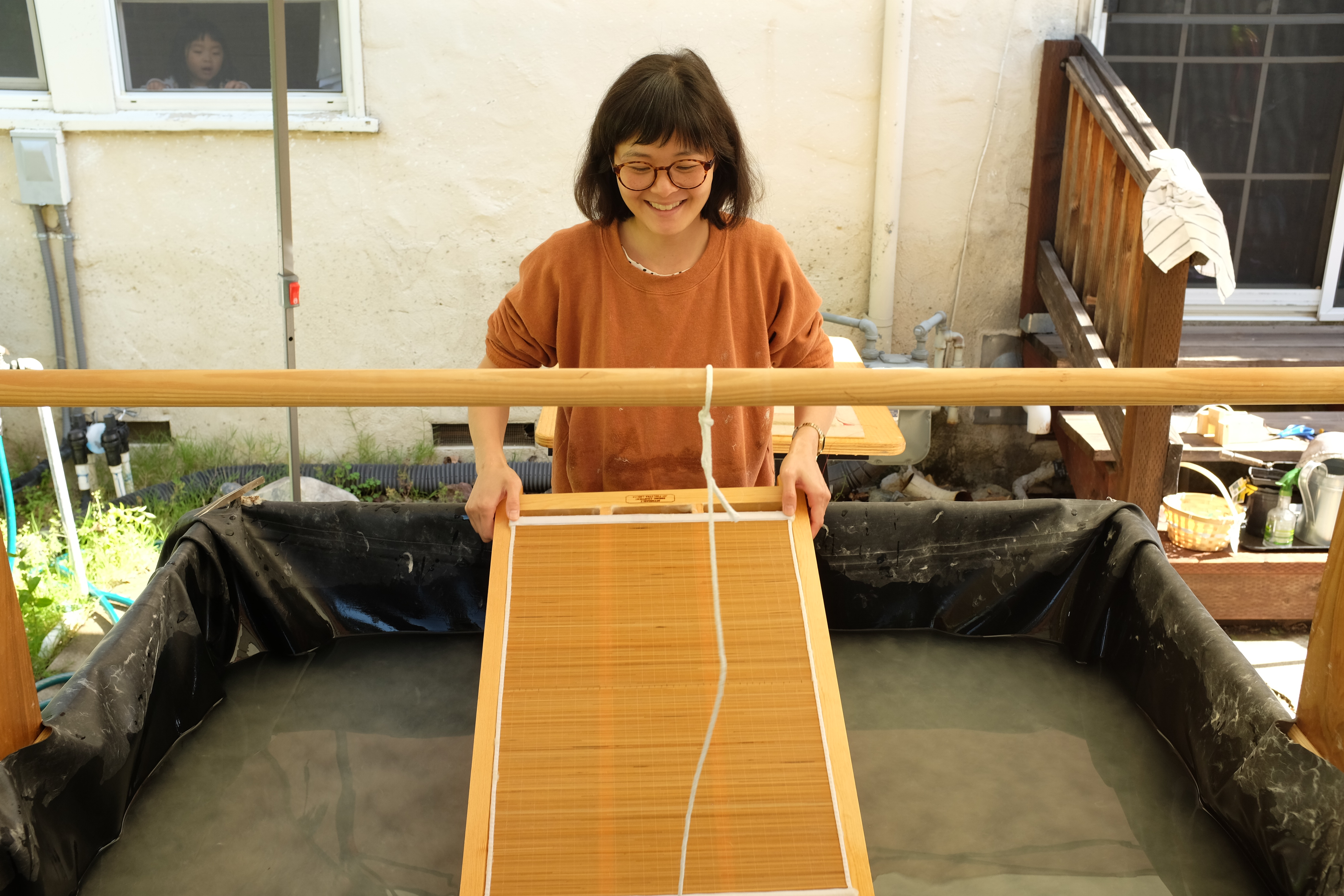 Artist Steph Rue pulling a sheet of handmade paper