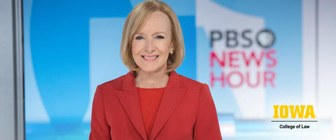 Judy Woodruff center focus in red shirt and blazer with PBS News Hour screen in the background. Iowa College of Law logo in lower right corner