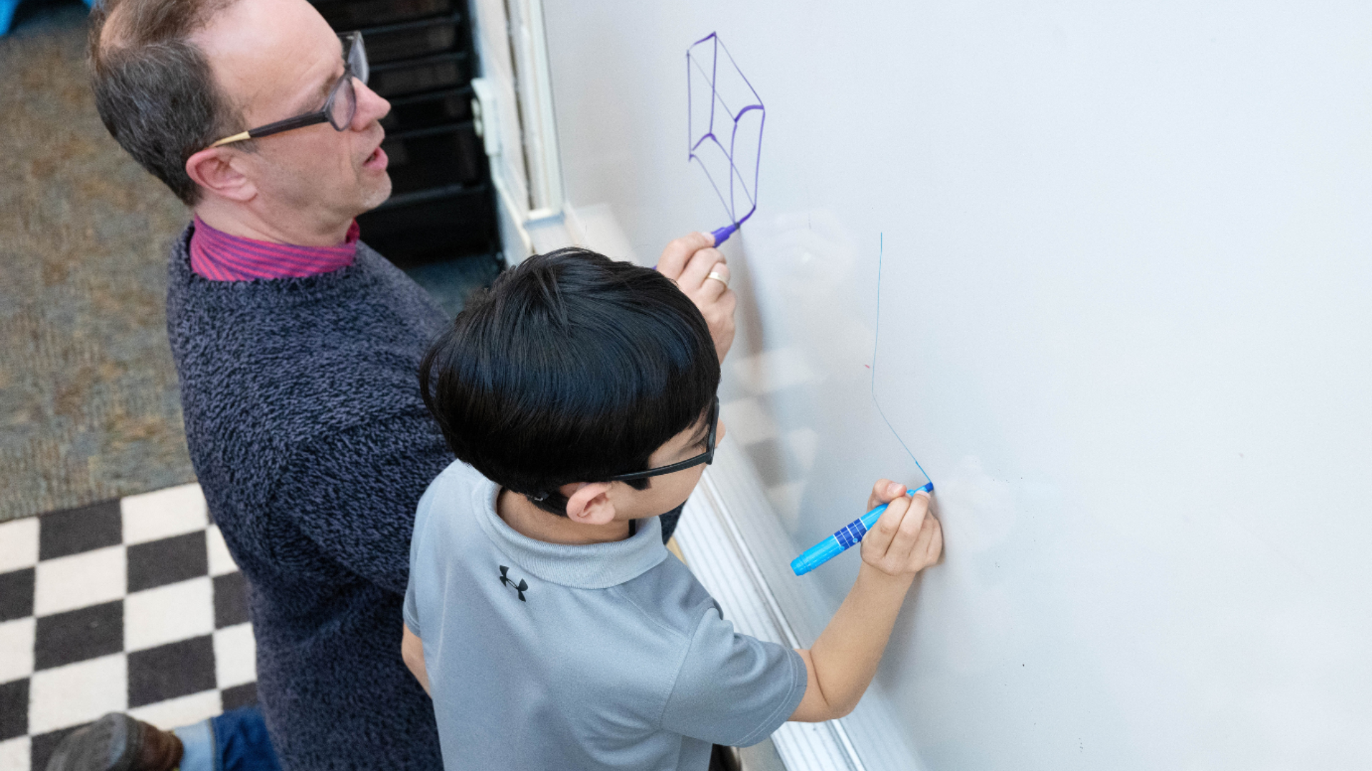 man and boy drawing on white board